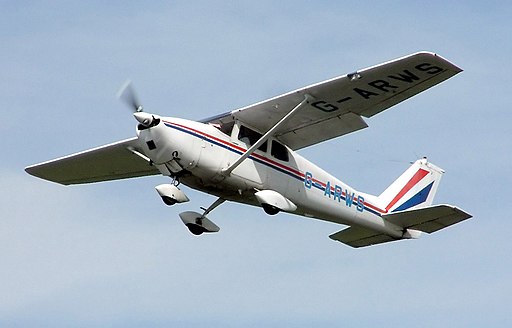 Cessna 175 light aircraft flying against background of blue sky