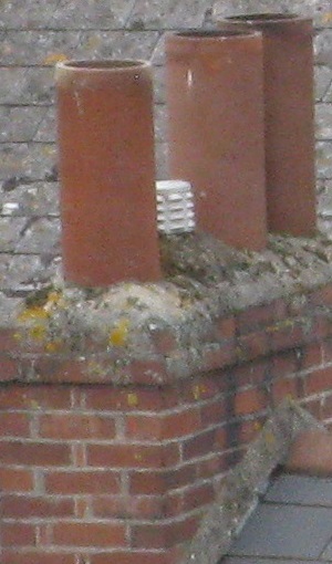 Three dark red cylindrical chimneypots